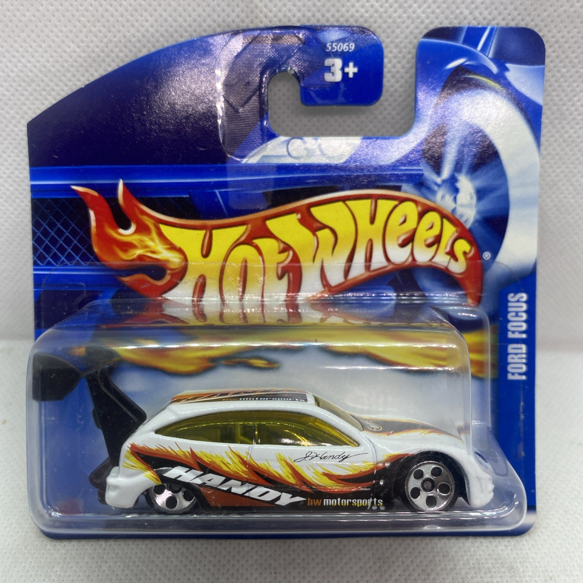 Hot Wheels die-cast Ford Focus car in blister pack, white body with flame decals and yellow windows.