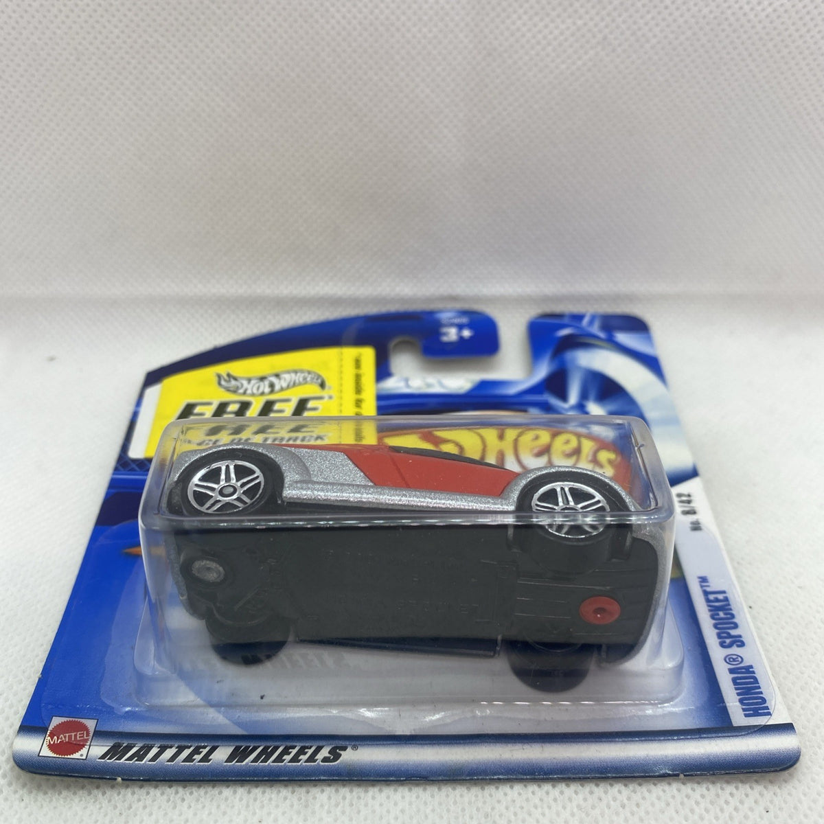 Hot Wheels blister card showing red and gray car under clear plastic and Mattel Wheels logo