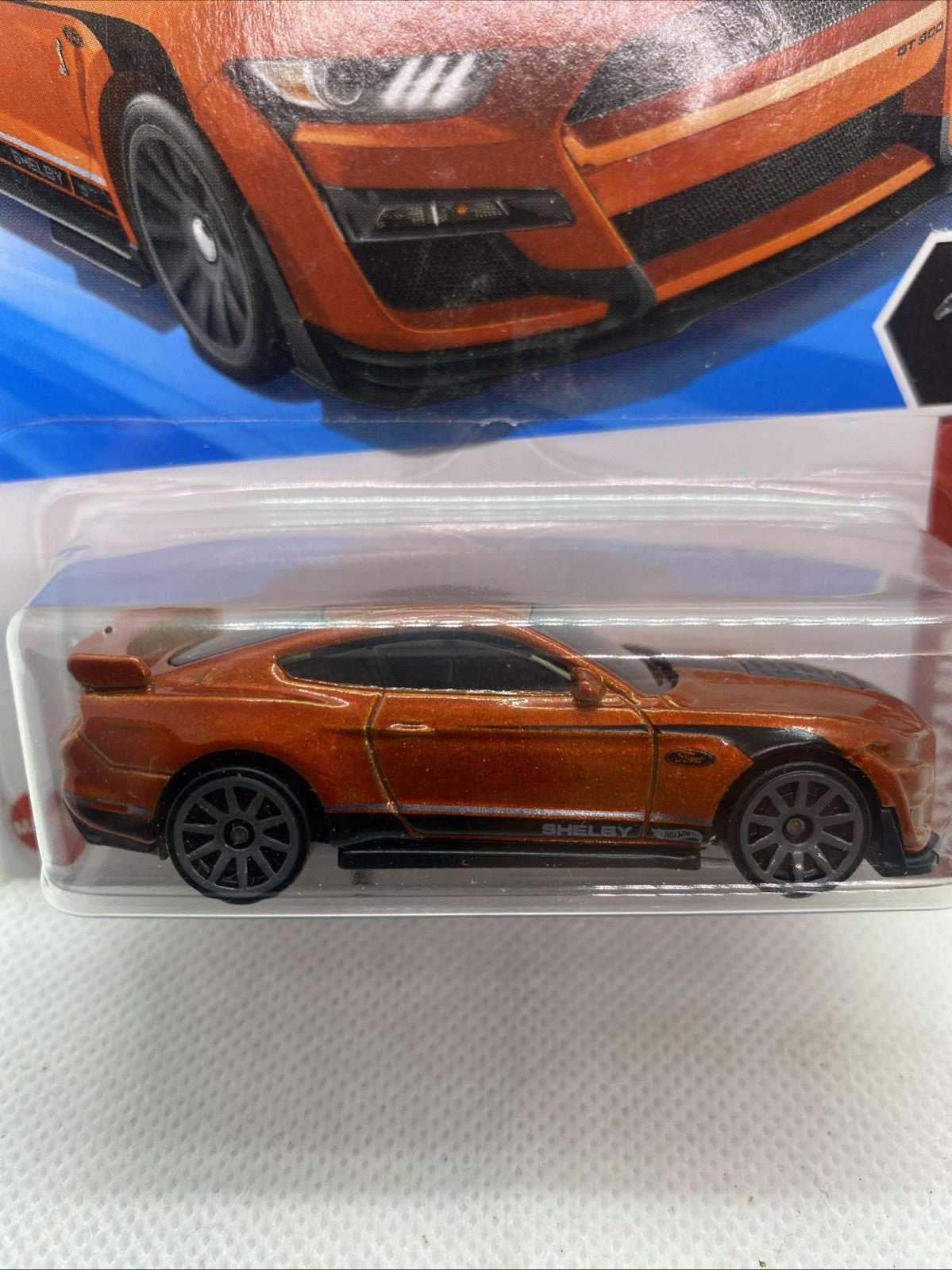 Hot Wheels die-cast Mustang Shelby GT500 in blister, orange body, side profile.