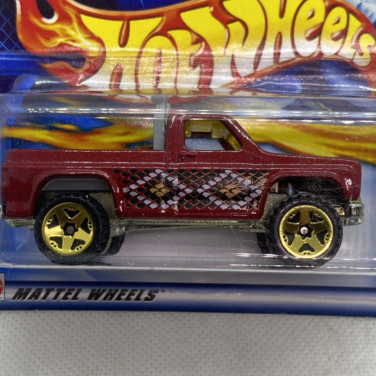 Hot Wheels maroon pickup close-up in blister pack, flame decals and black mesh grille, yellow wheels