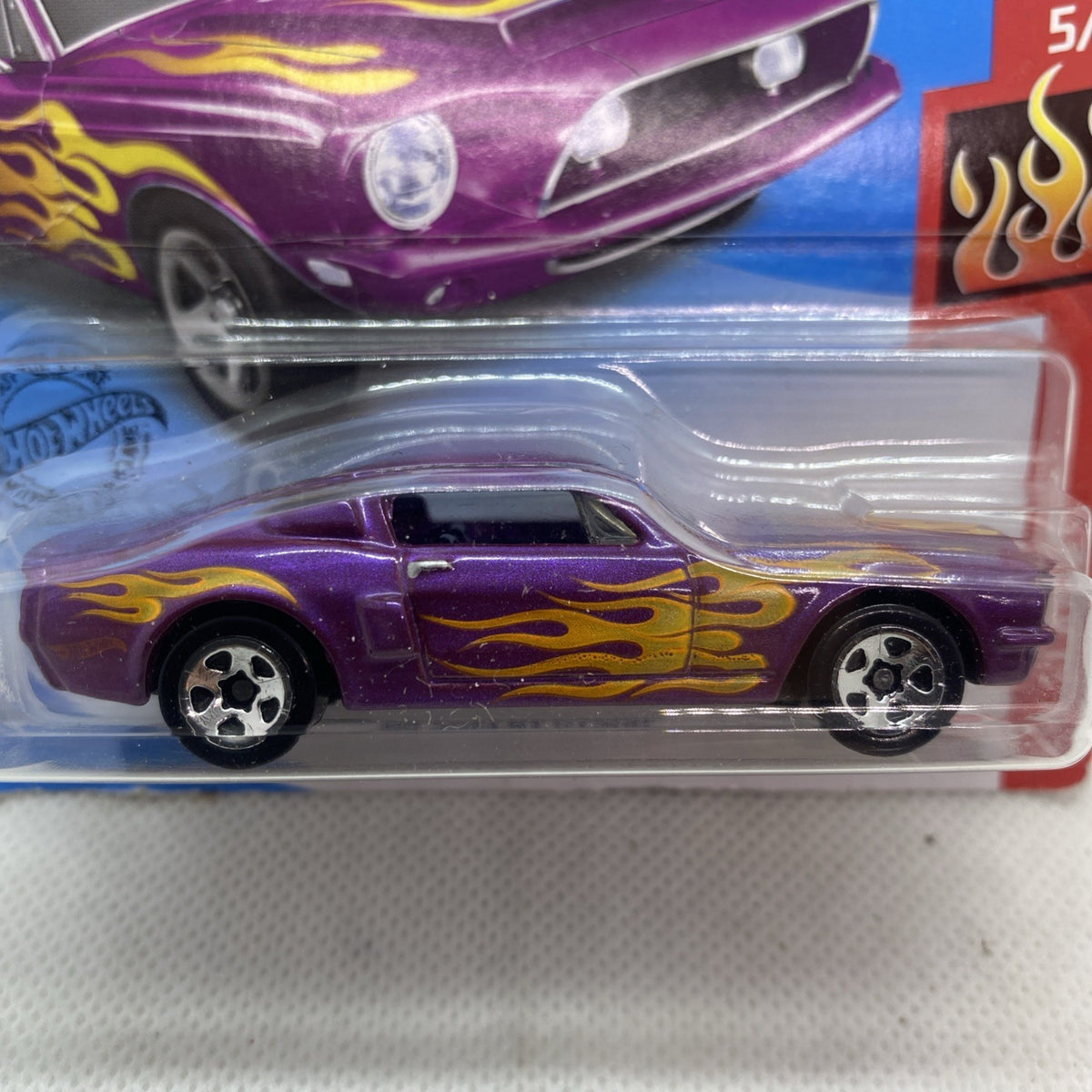 Hot Wheels purple die-cast car with yellow flames, front and side view in clear blister
