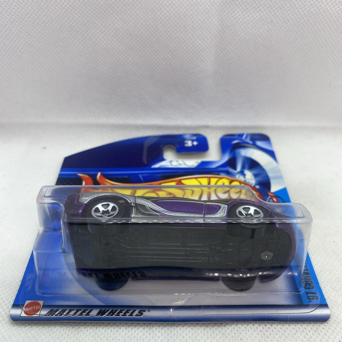 Black base Corvette die-cast in clear blister, purple trim on blue Hot Wheels card