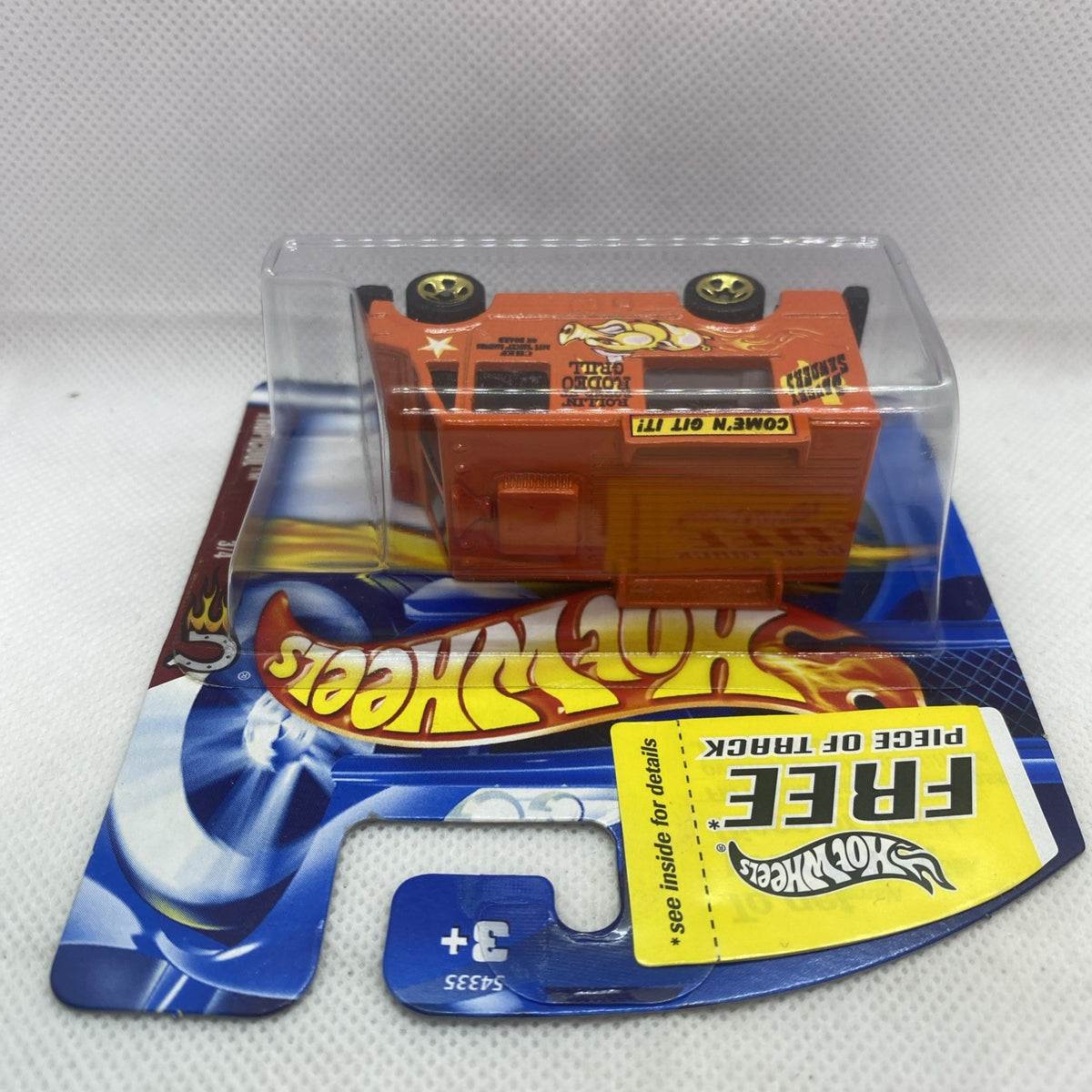 Orange toy truck visible through clear blister on blue Hot Wheels card