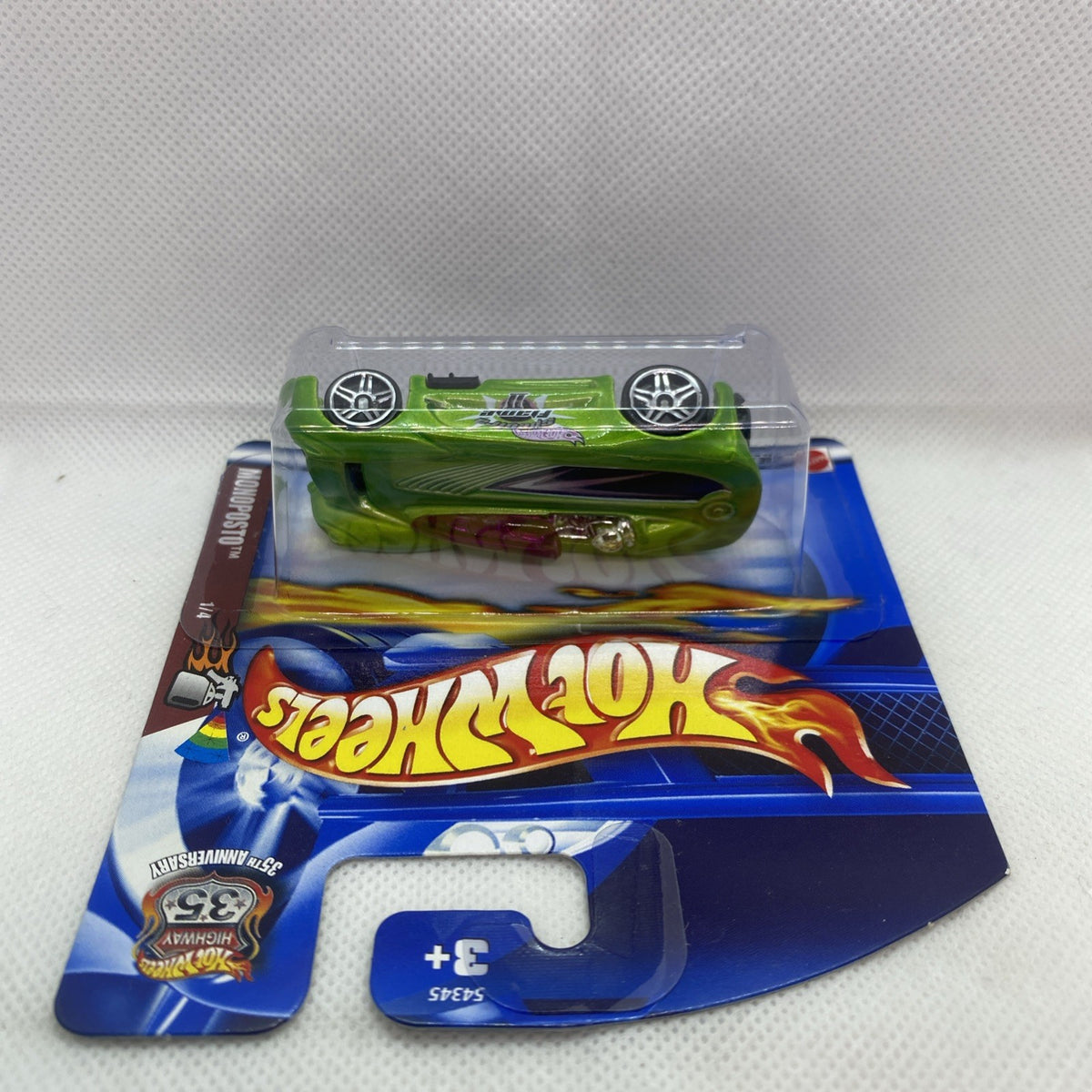 Green race car in blister pack on blue card, viewed from above