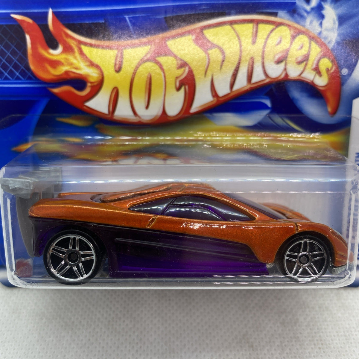 Hot Wheels die-cast car, orange body with flame print, purple base, sealed blister close-up