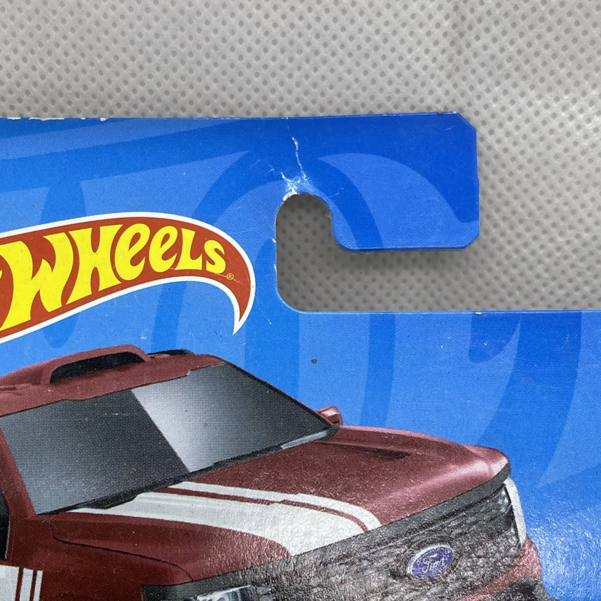 Maroon die-cast pickup truck toy in clear blister, close-up of black hood