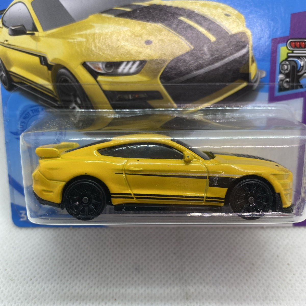 Yellow and black die-cast muscle car in blister, close-up side view