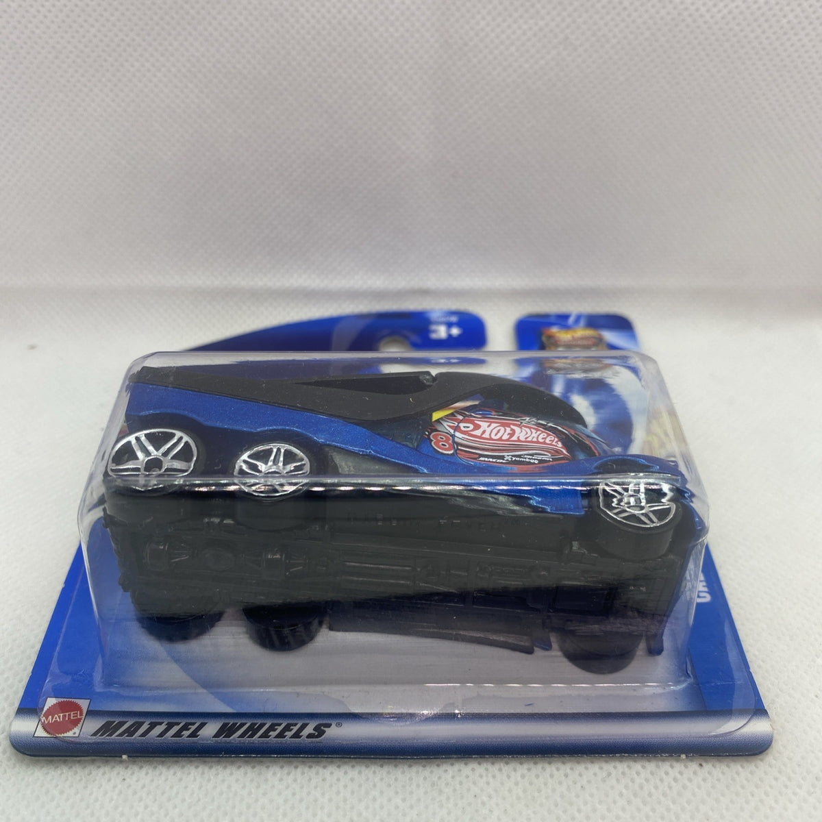 Blue Hot Wheels die-cast car in blister pack, side view with flame hood