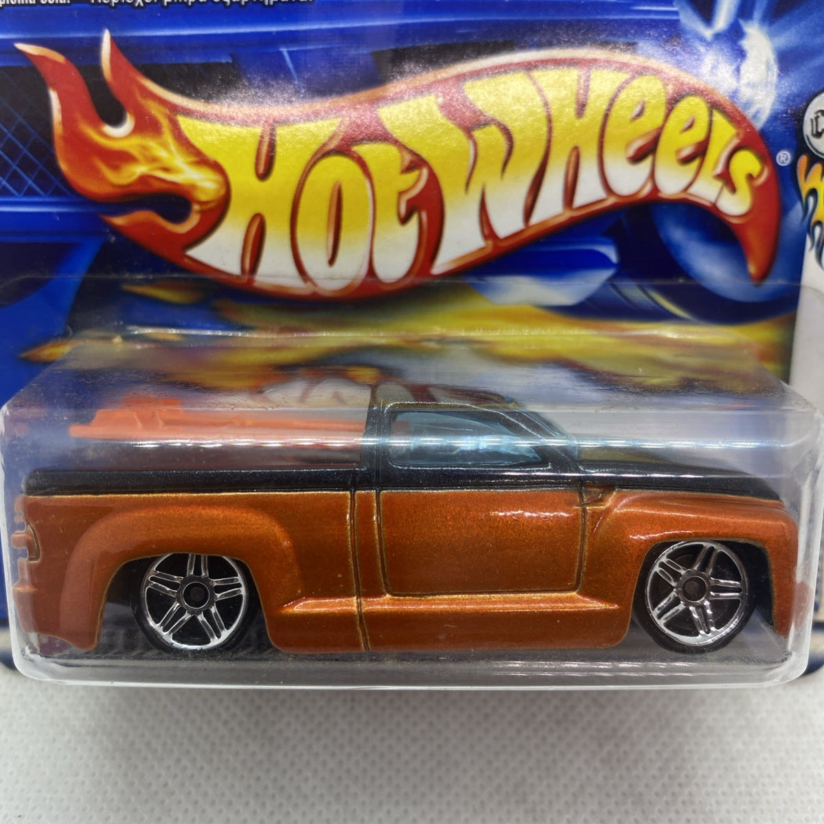 Hot Wheels die-cast car close-up in blister, orange body with chrome wheels and black windows.